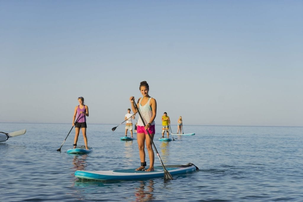 A group of friends paddle boarding in Mykali Bay, Samos, Greece