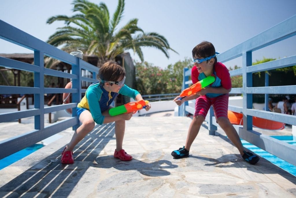 Brothers having a water fight by the swimming pool at the Zefiros Beach Hotel in Samos