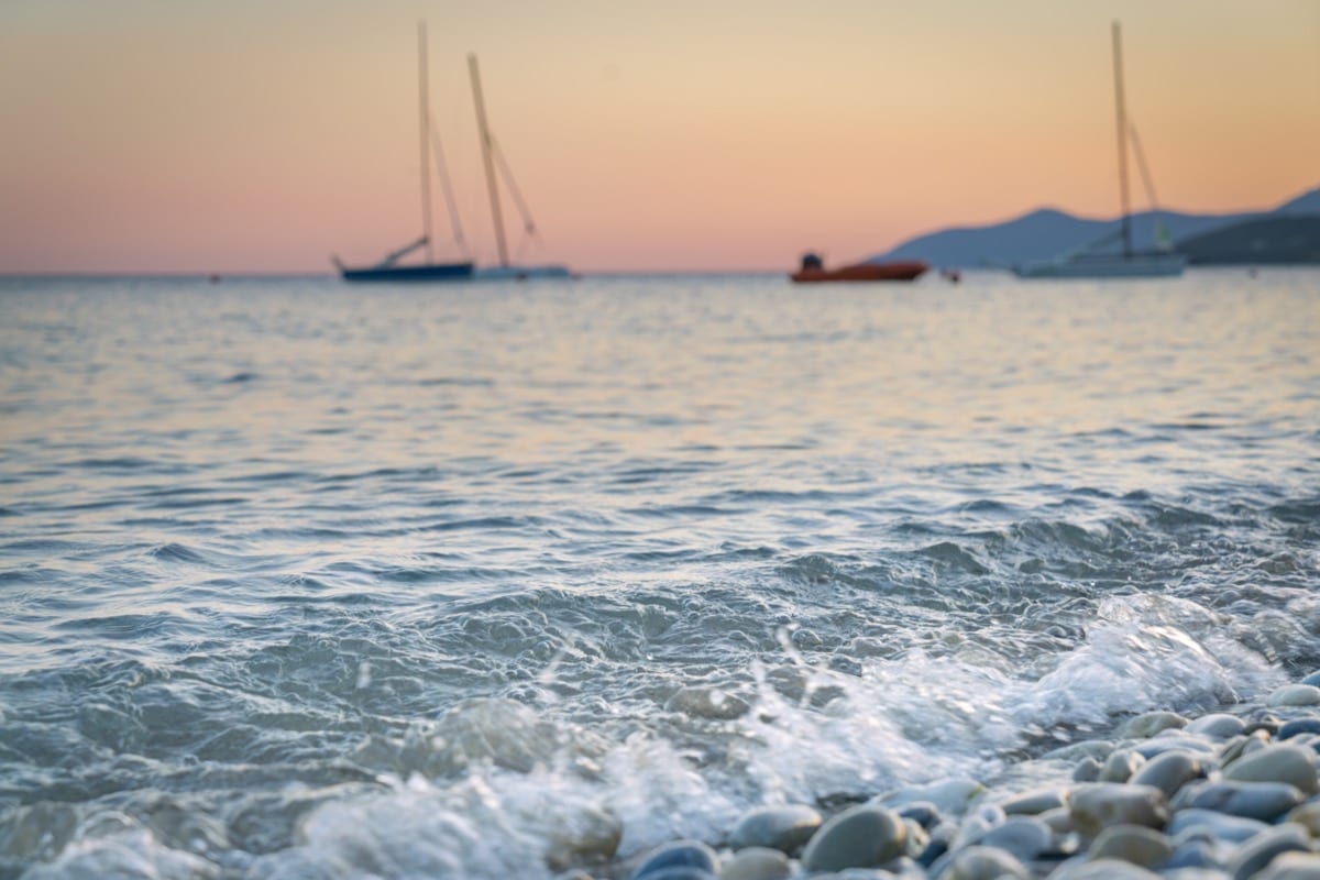 The waves lapping the beach in Samos, Greece as the sun sets on a summer's day