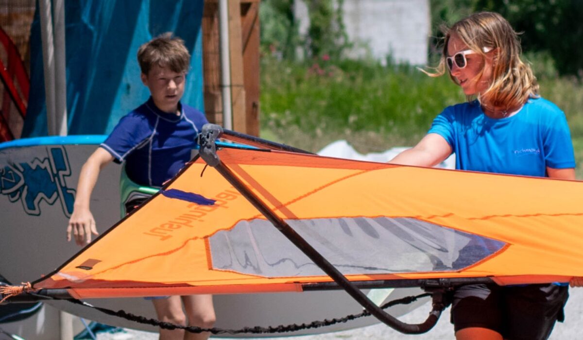 Richmond guest and Richmond staff carrying a windsurf board