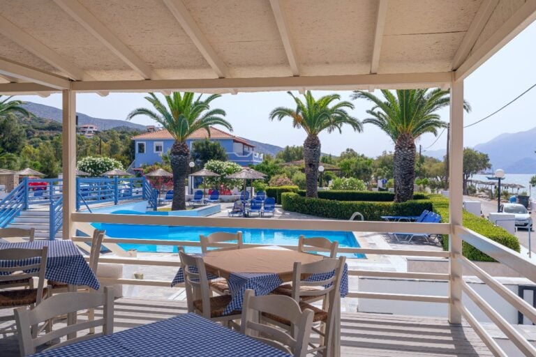 View from the pool side veranda displaying table, chars and pool
