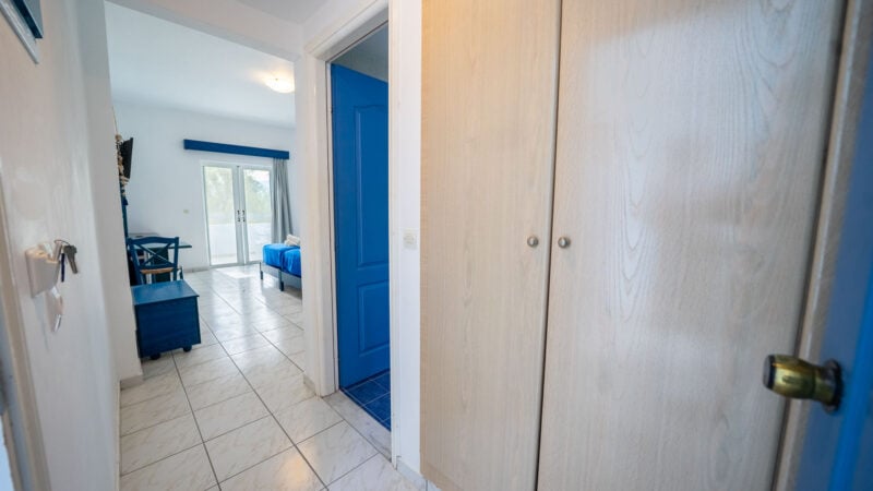 Hotel Room with brown storage cupboard doors and a blue toilet door.