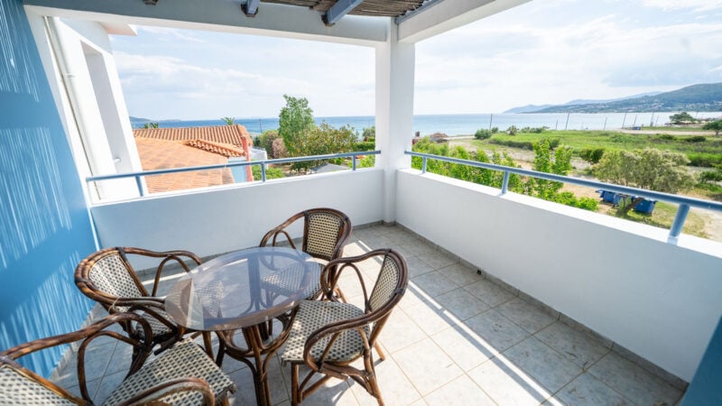 Corner Suite balcony with table and wooden chairs and sea views from balcony.