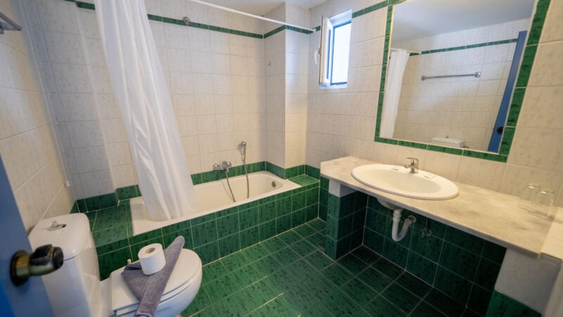 Corner Suite bathroom with sink, toilet and shower-over-bath on green tiling