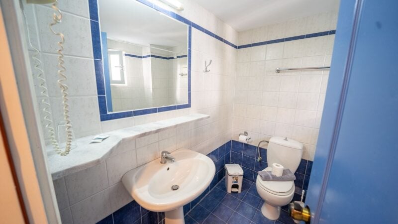 Reception Level bathroom with toilet, sink and shower-over-bath and blue tiling.