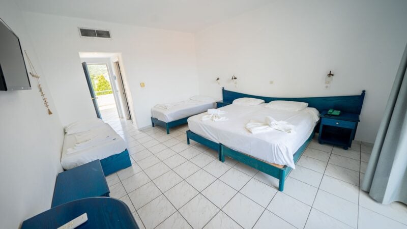 An Upper-Level Room with four twin beds in total. Flatscreen TV on the wall and balcony with views of the sea.