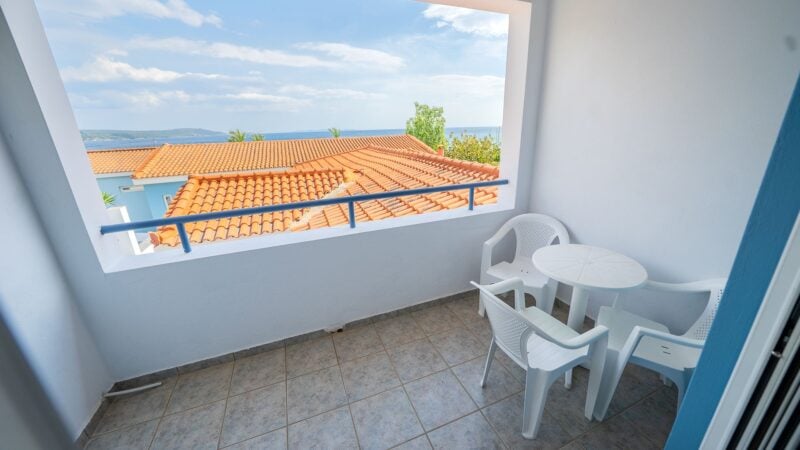 An Upper-Level Room balcony with white table and chairs overlooking the top of the hotel