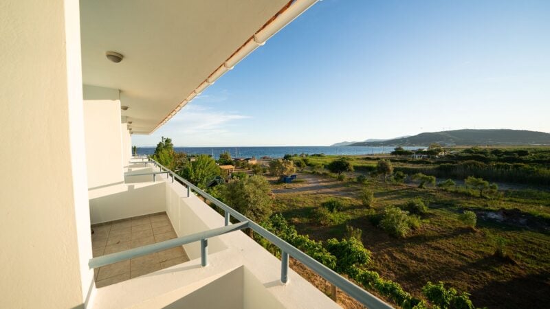 A row of balconies on the Upper-Level of the hotel overlooking the sea and vegetation next to hotel