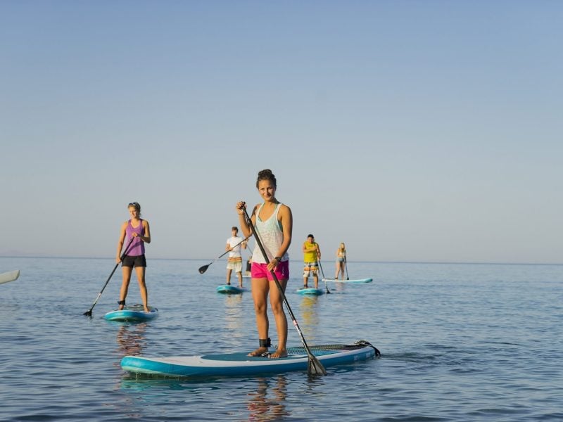 A group of friends paddle boarding in Mykali Bay, Samos, Greece